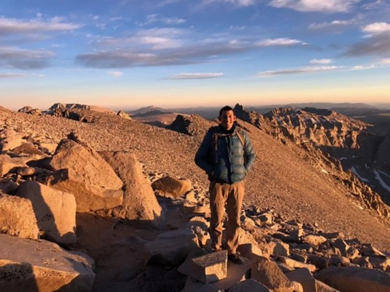 man in jacket standing on mountain