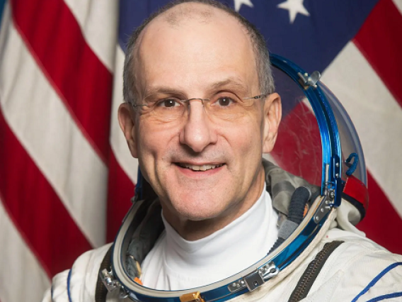A headshot of Donald Pettit in his spacesuit in front of an American flag