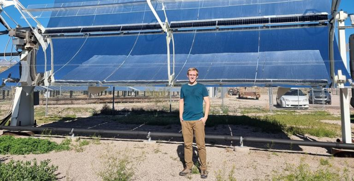 Student standing in front of solar panel