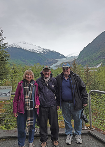 three people standing in front of glacier
