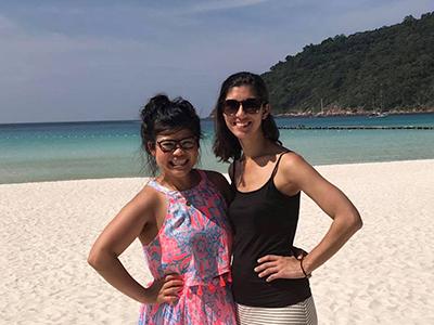 Two smiling women on a tropical beach with white sand and blue water