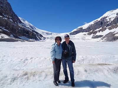 A woman and a man in winter gear on top of a snow-covered glacier