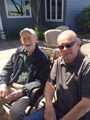 Two men in patio chairs, outside on a sunny day