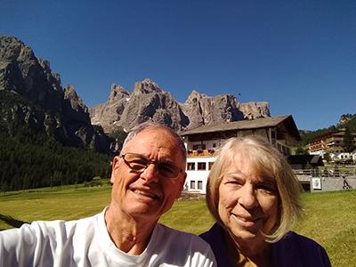 Tony Durando and his wife, Nann, in a field with a chateau and dark mountains showing behind them