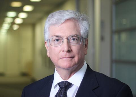 A man with white hair and glasses wearing a suit