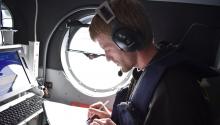 Joe Schlosser takes notes aboard a plane