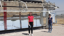 Mikah Inkawhich and Kerri Hickenbottom standing in front of a solar-powered desalination system, which looks like a giant mirror.