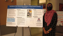 Engineering student Noreen Qureshi standing in front of a research poster during the REAL Work Program
