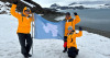 three people in artic setting, holding a flag