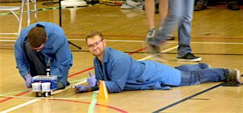Two chemical engineering students construct a Chem-E-Car in a gymnasium