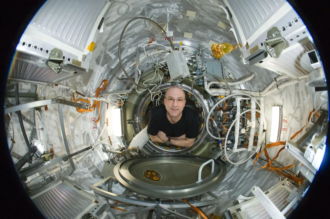 An older man floats inside a space vehicle.