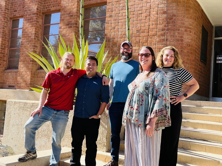 group of people, standing in front of a brick building with steps