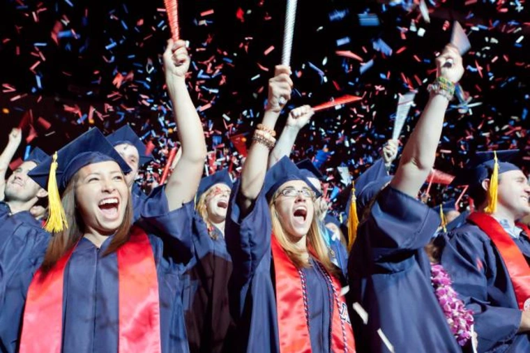 student wearing regalia, cheering