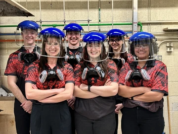 six people, wearing protect lab gear, wearing red and black shirts