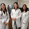 Three people wearing white lab coats, smiling