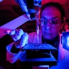 A woman looks at a microscope.