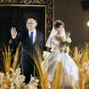 wedding photo, man in black suit with blue tie, woman in white dress holding flowers